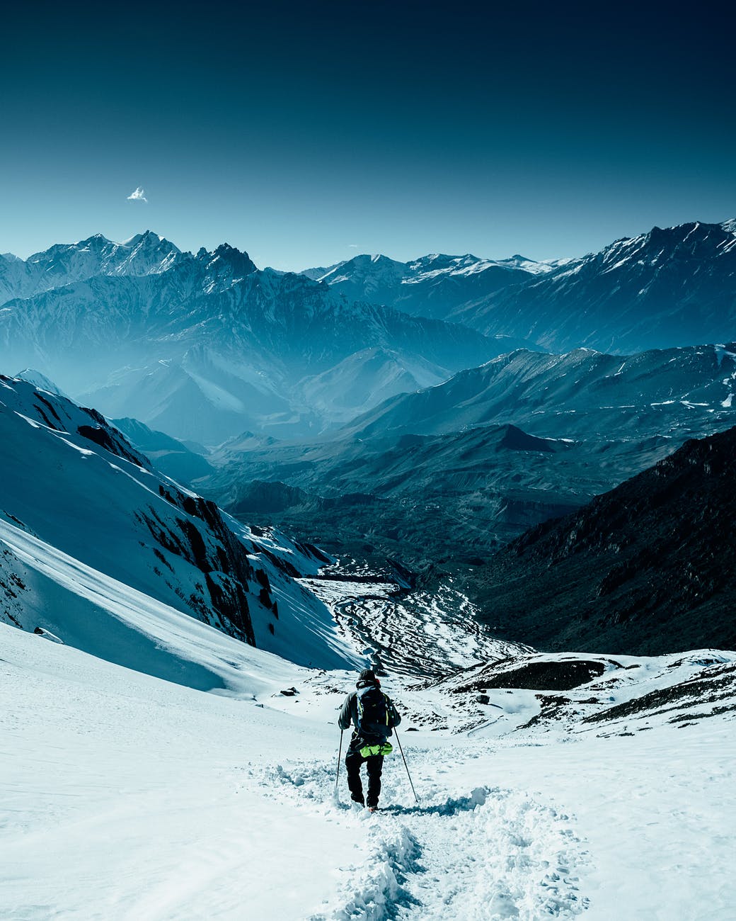 person in black jacket and blue pants walking on snow covered ground